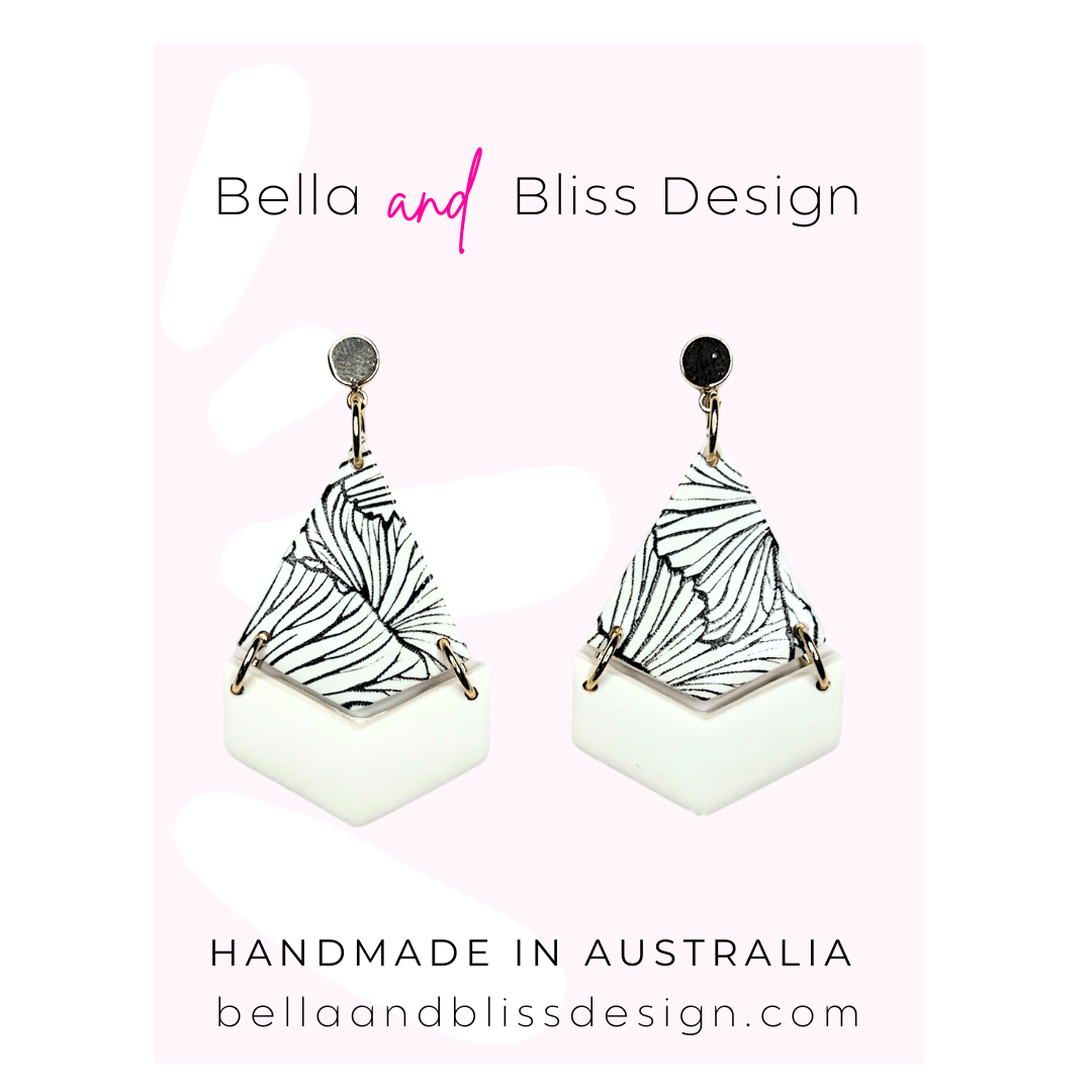 Pair of earrings with black and white with gold top on a light pink background with Bella and Bliss Design branding.