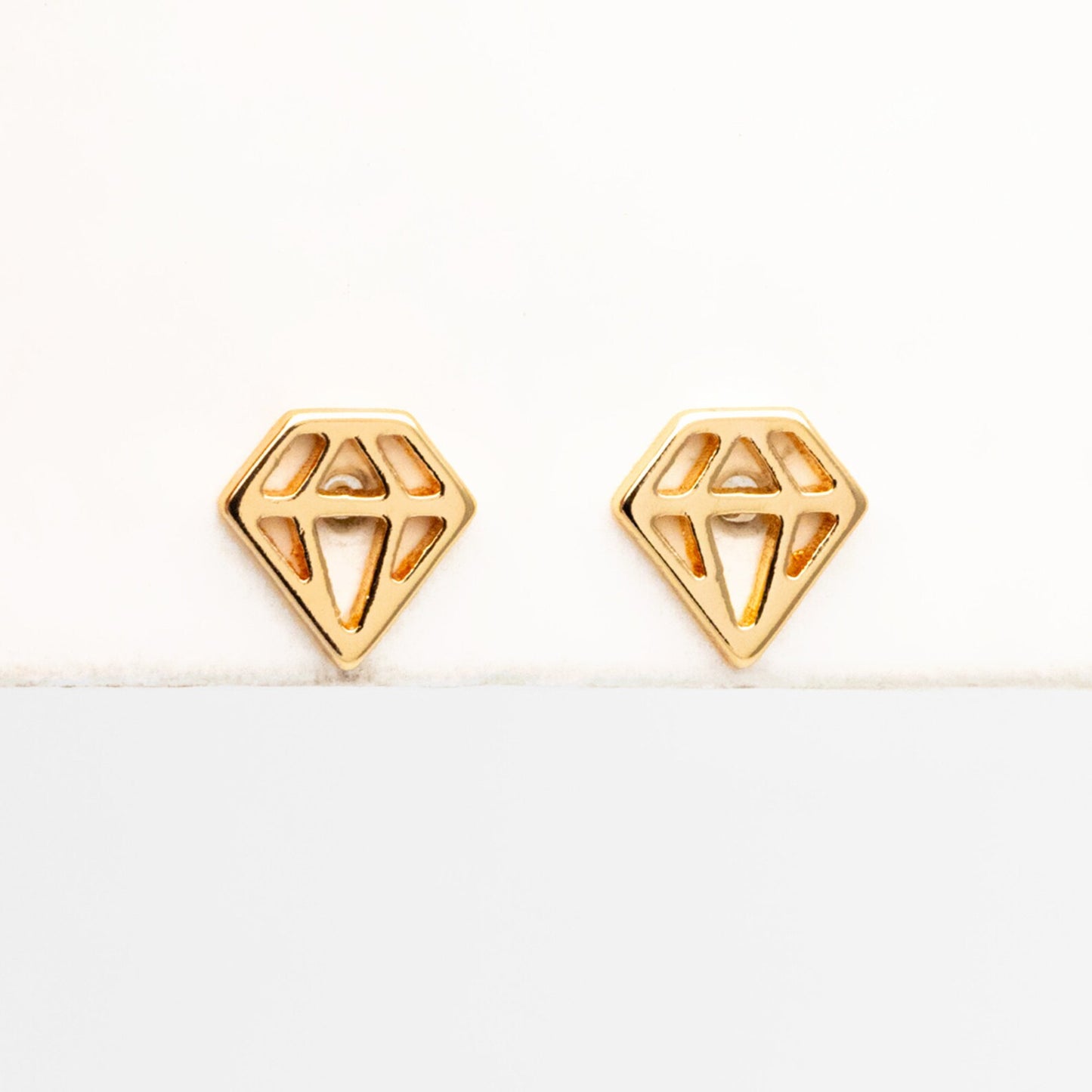 A pair of 18K gold plated mini stud earrings displayed on a branded card with 'Bella and Bliss Design' written on it.