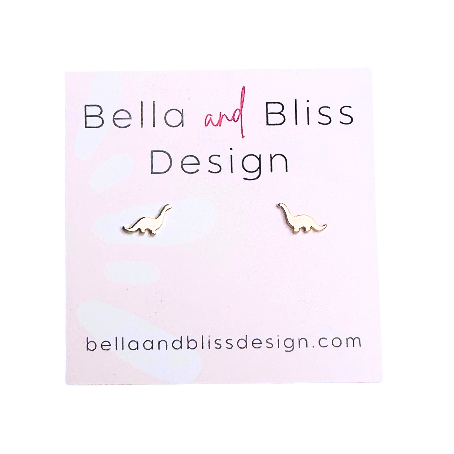 A pair of gold mini stud earrings with a dinosaur design, displayed on a pink background with the brand name 'Bella and Bliss Design'.