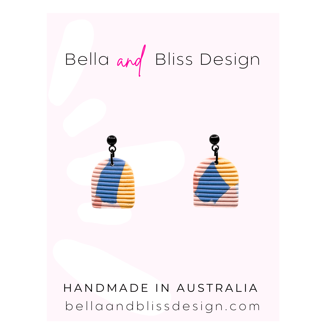 Colorful earrings with 'Bella and Bliss Design' branding on a light pink background.