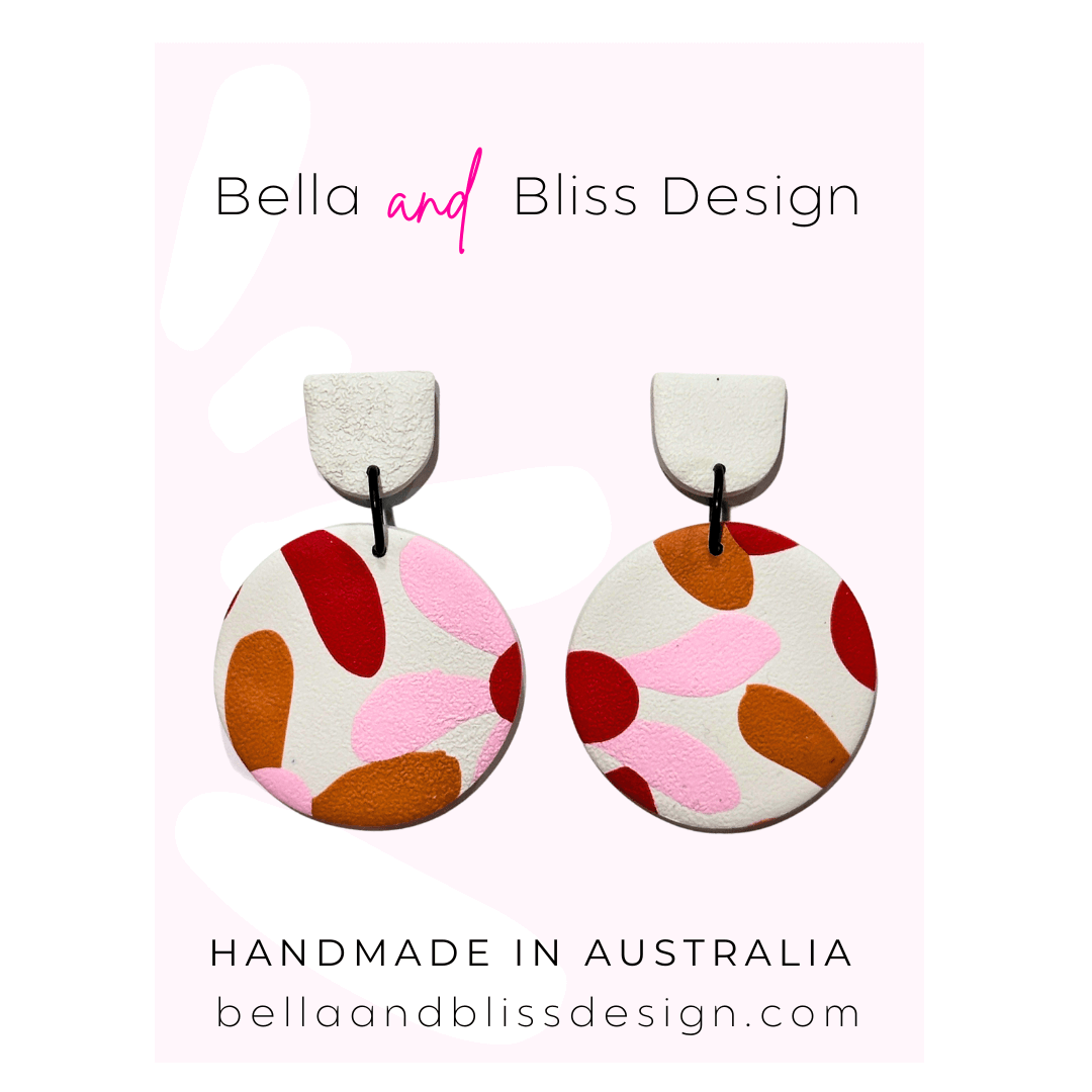 Pair of colorful earrings with 'Bella and Bliss Design' branding on a pink background.