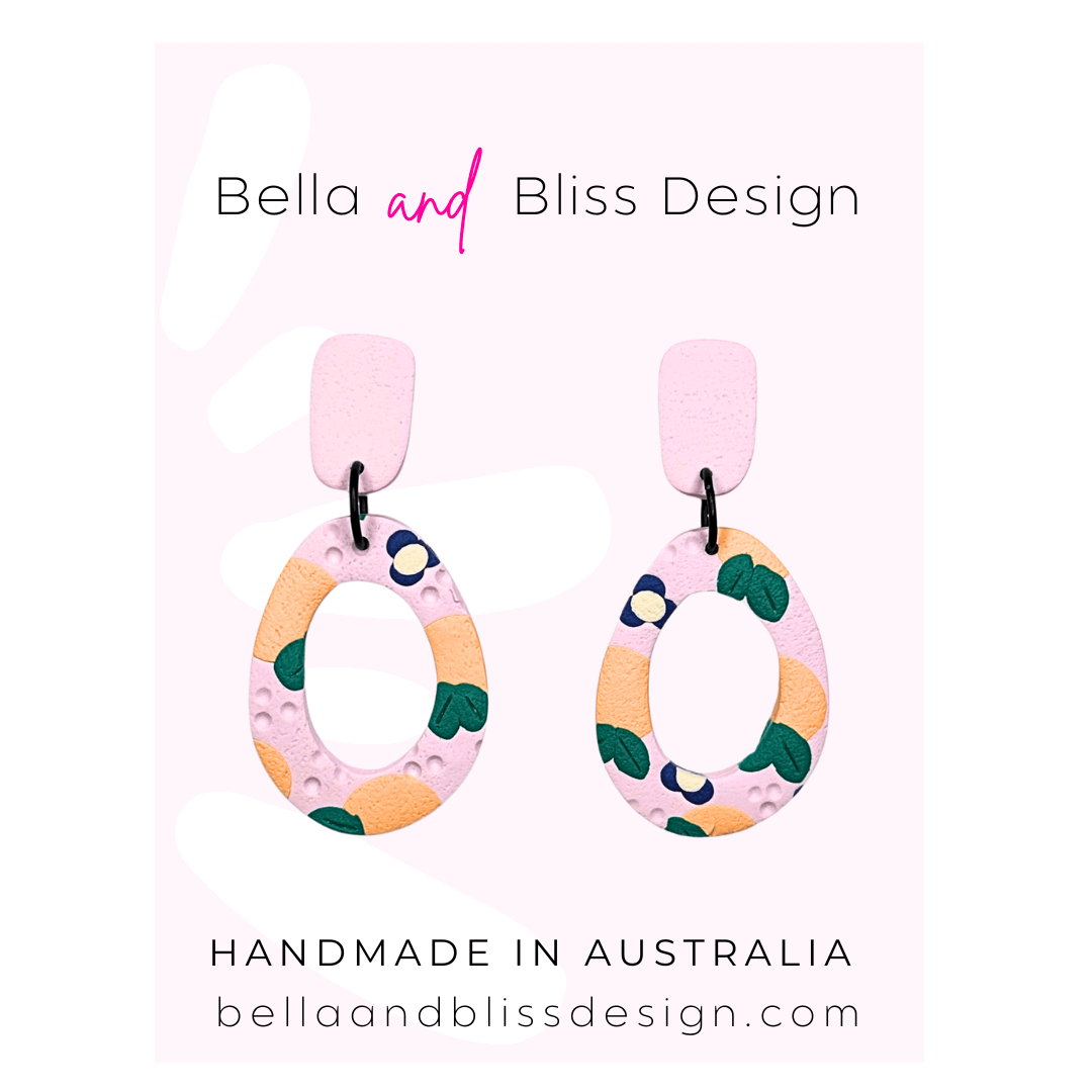 Peach Blossom Dangle Earrings with 'Bella and Bliss Design' branding on a pink background