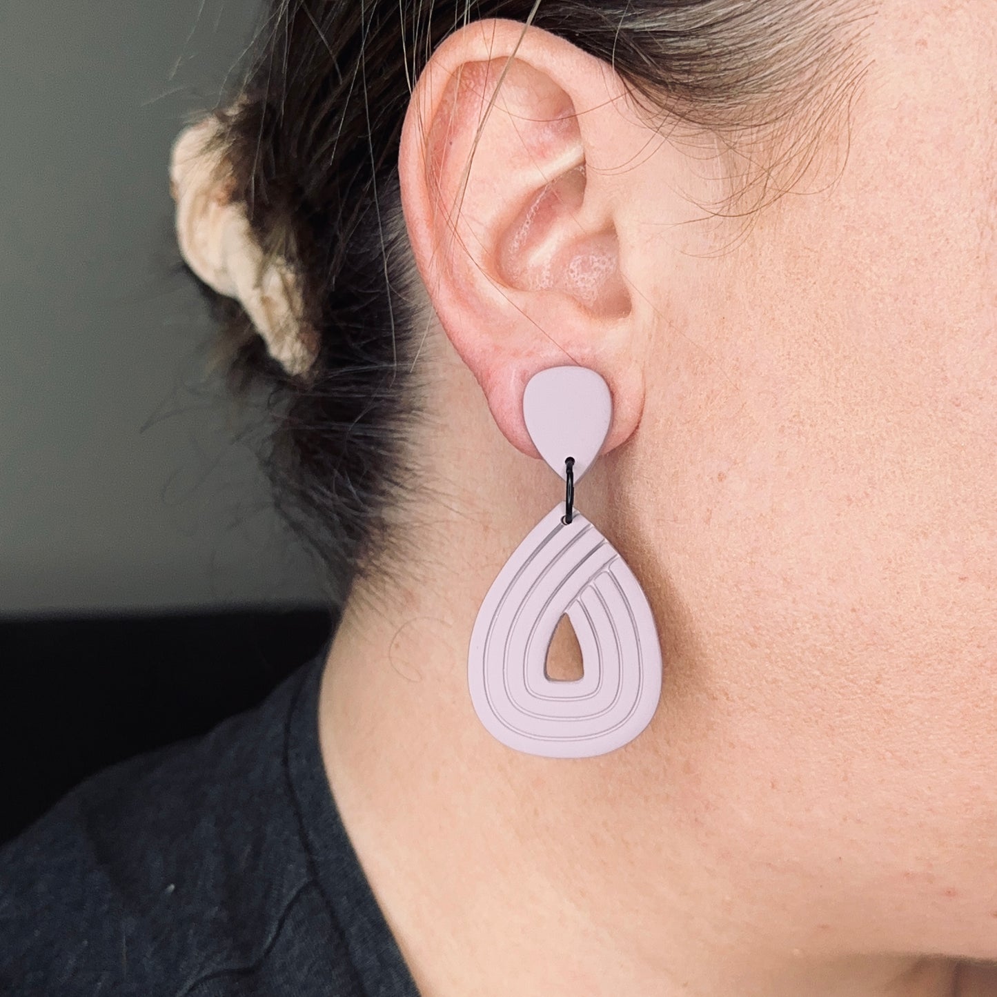 Purple earrings on a person for sizing
