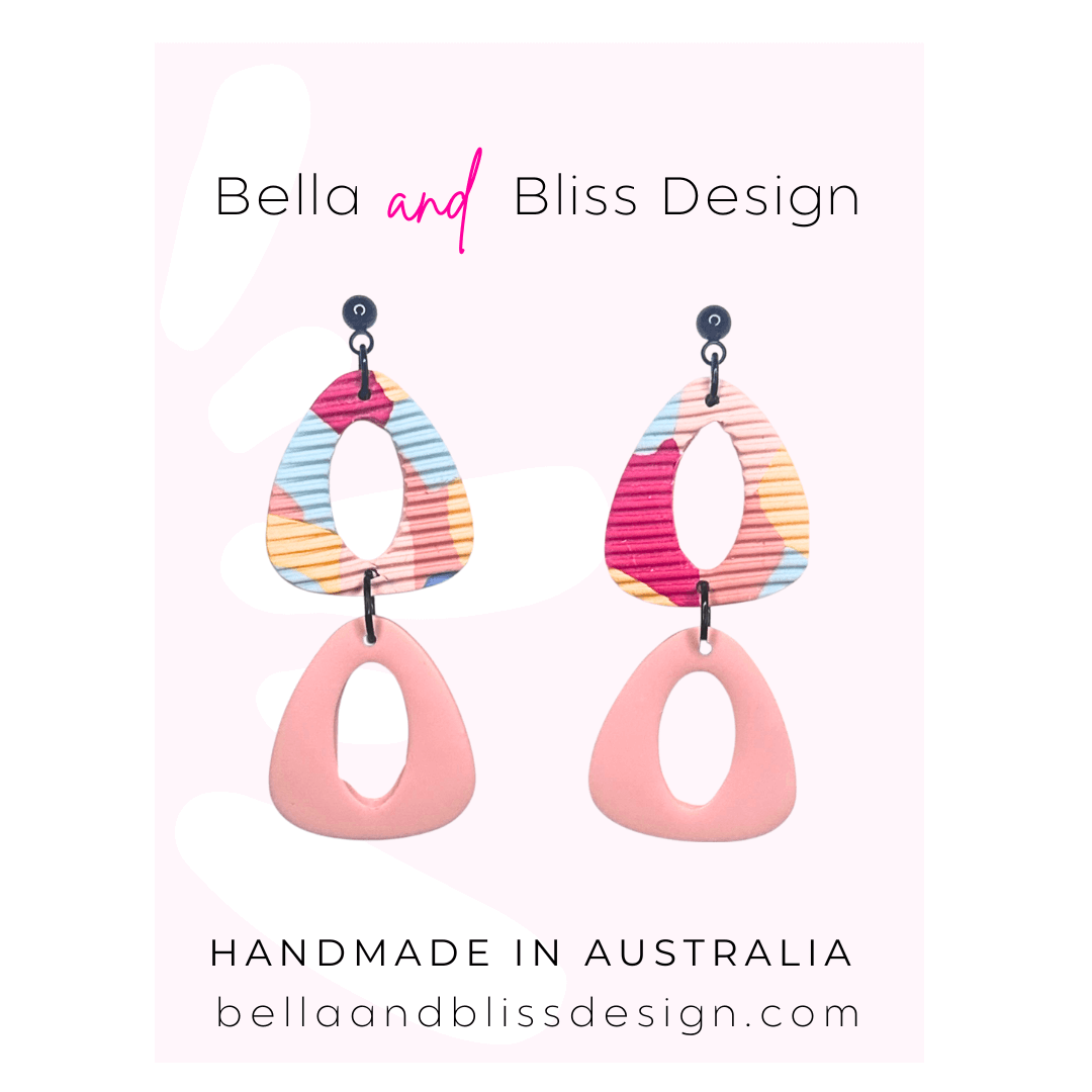 Colorful earrings with 'Bella and Bliss Design' branding on a pink background