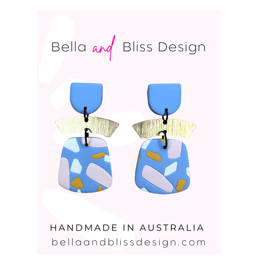 Colorful earrings with geometric design on a light pink background, featuring 'Bella and Bliss Design'.