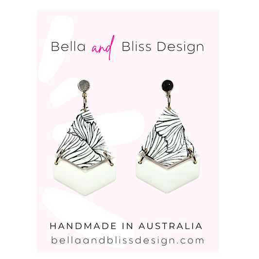Pair of earrings with black and white with gold top on a light pink background with Bella and Bliss Design branding.