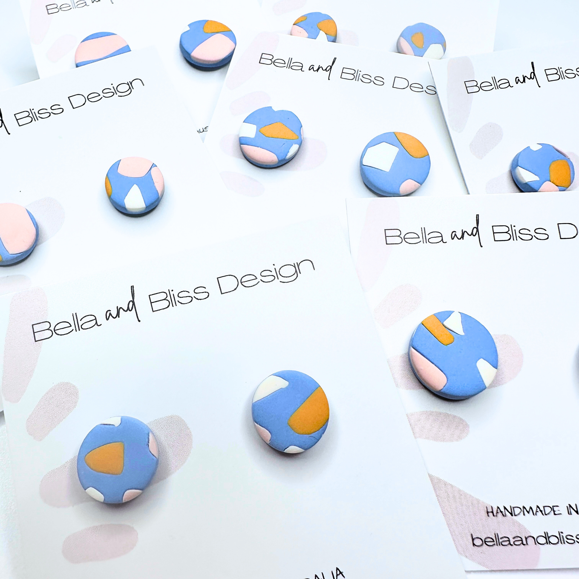 Colorful geometric earrings on a branded card with 'Bella and Bliss Design' text.