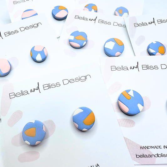 Colorful geometric earrings on a branded card with 'Bella and Bliss Design' text.