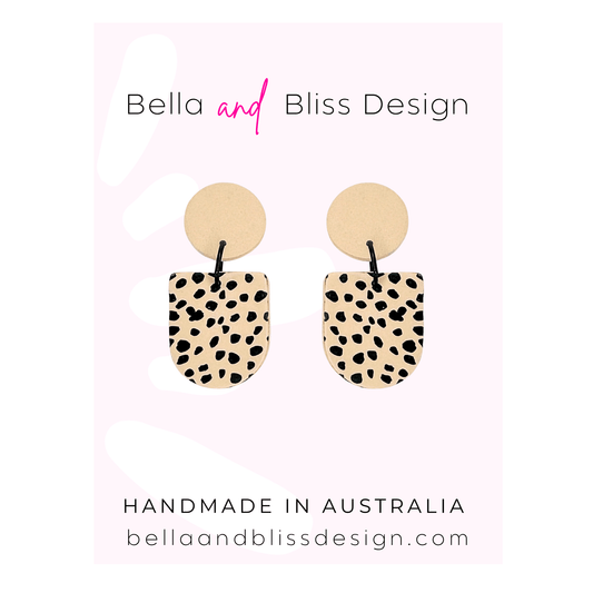 Pair of earrings with spotted design on a pink background with Bella and Bliss Design branding.