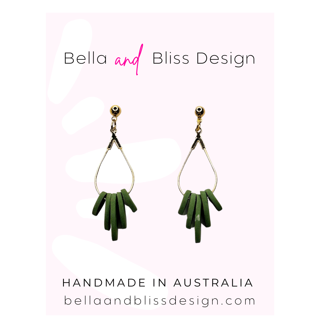 Green earrings with gold hooks on a light pink background, featuring 'Bella and Bliss Design'.