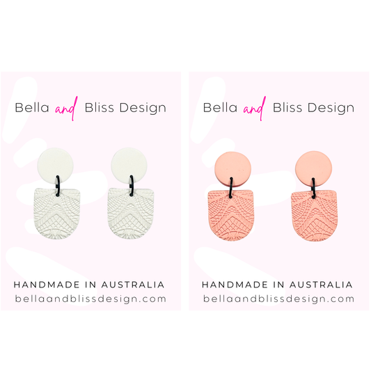 Pair of white textured earrings and pink textured earrings with 'Bella and Bliss Design' branding on a light pink background.