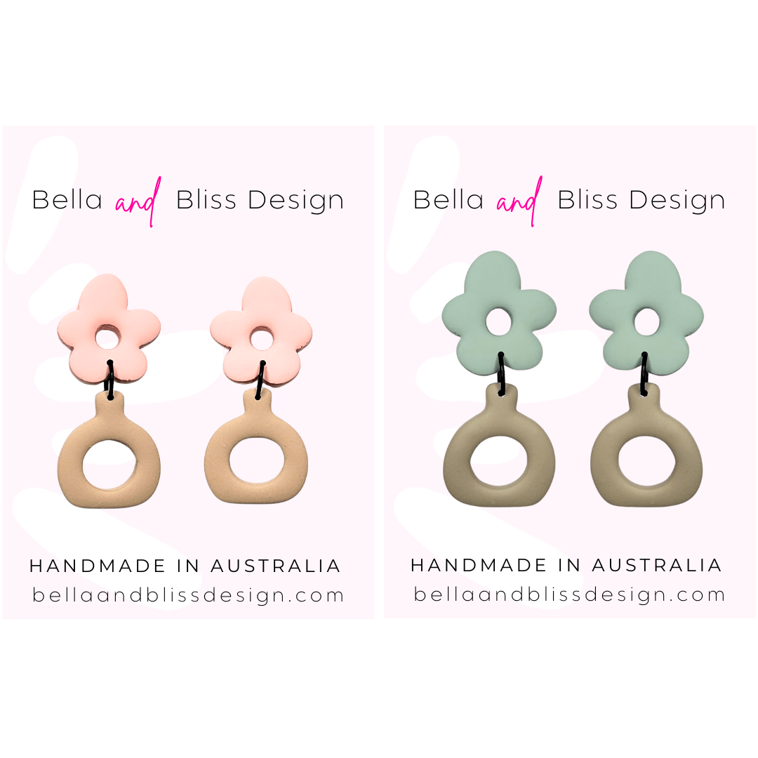 Flower-shaped earrings with pink floral tops and beige circular bases on a light pink background, featuring 'Bella and Bliss Design'.