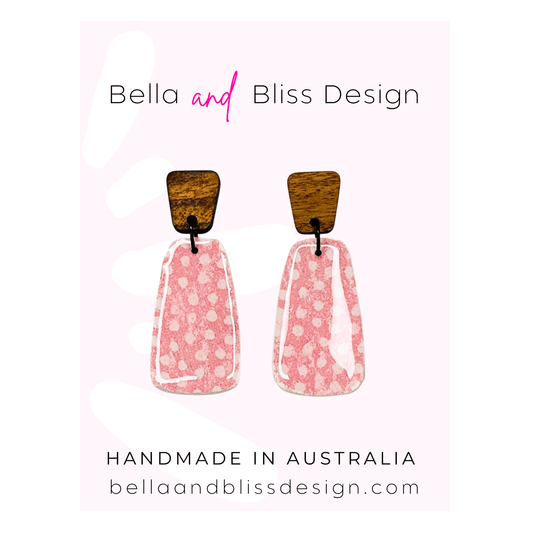 Pair of pink earrings with wooden tops on a white background, branded as Bella and Bliss Design.