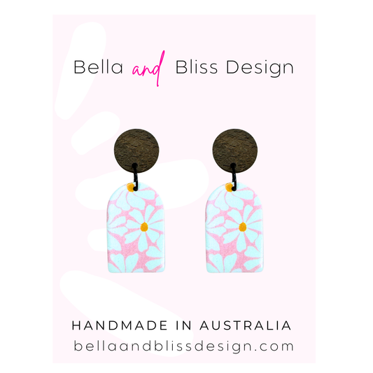 Earrings with floral design on a pink background, branded as Bella and Bliss Design.