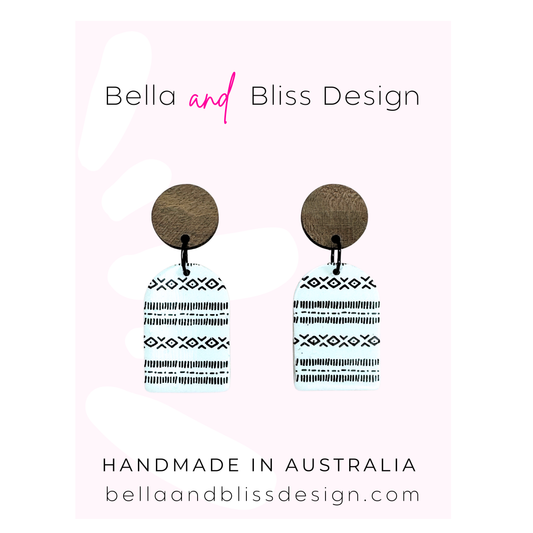 Wooden earrings with patterned extensions on a light pink background, branded as Bella and Bliss Design.
