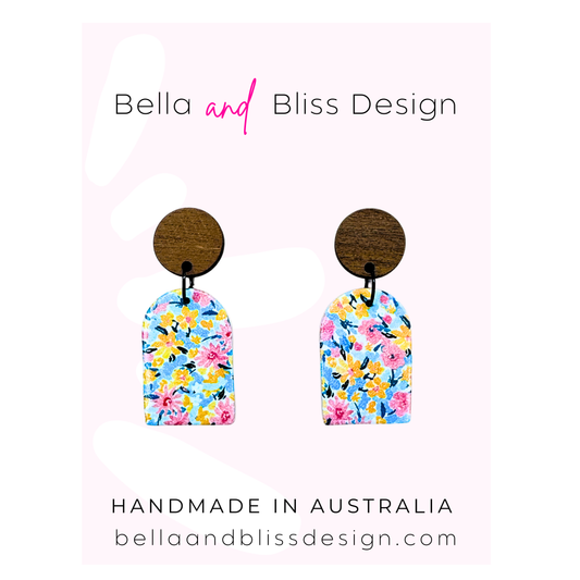 Floral earrings with wooden backing on a light pink background, branded 'Bella and Bliss Design'.