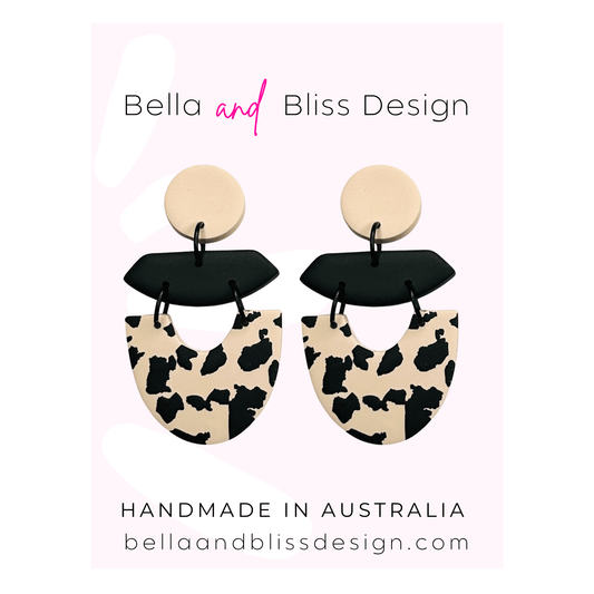 Pair of earrings with black and beige design on a pink background with 'Bella and Bliss Design' branding.