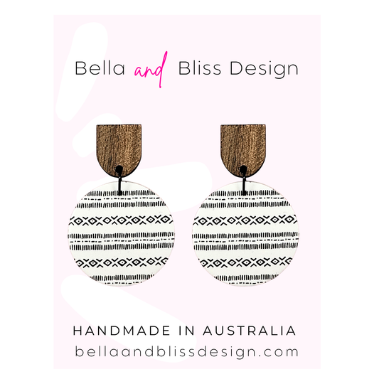 Wooden earrings with black patterns on a pink background, featuring 'Bella and Bliss Design'.