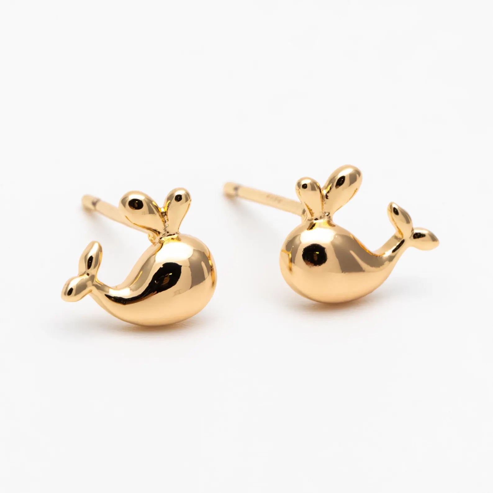 Gold whale-shaped earrings on a white background