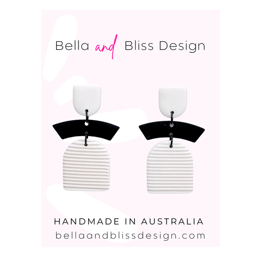 Black and white earrings with 'Bella and Bliss Design' branding on a light pink background.