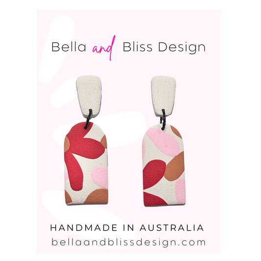 Pair of earrings with colorful design on a light pink background, featuring 'Bella and Bliss Design'.