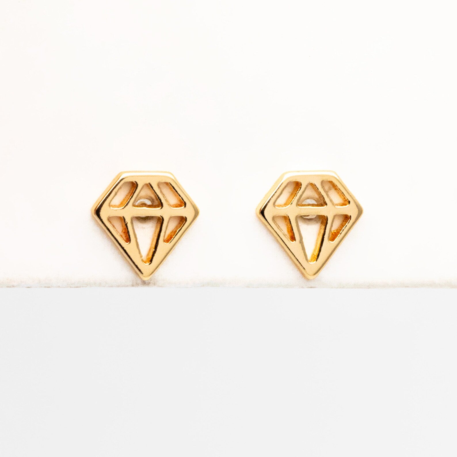 A pair of 18K gold plated mini stud earrings displayed on a branded card with 'Bella and Bliss Design' written on it.