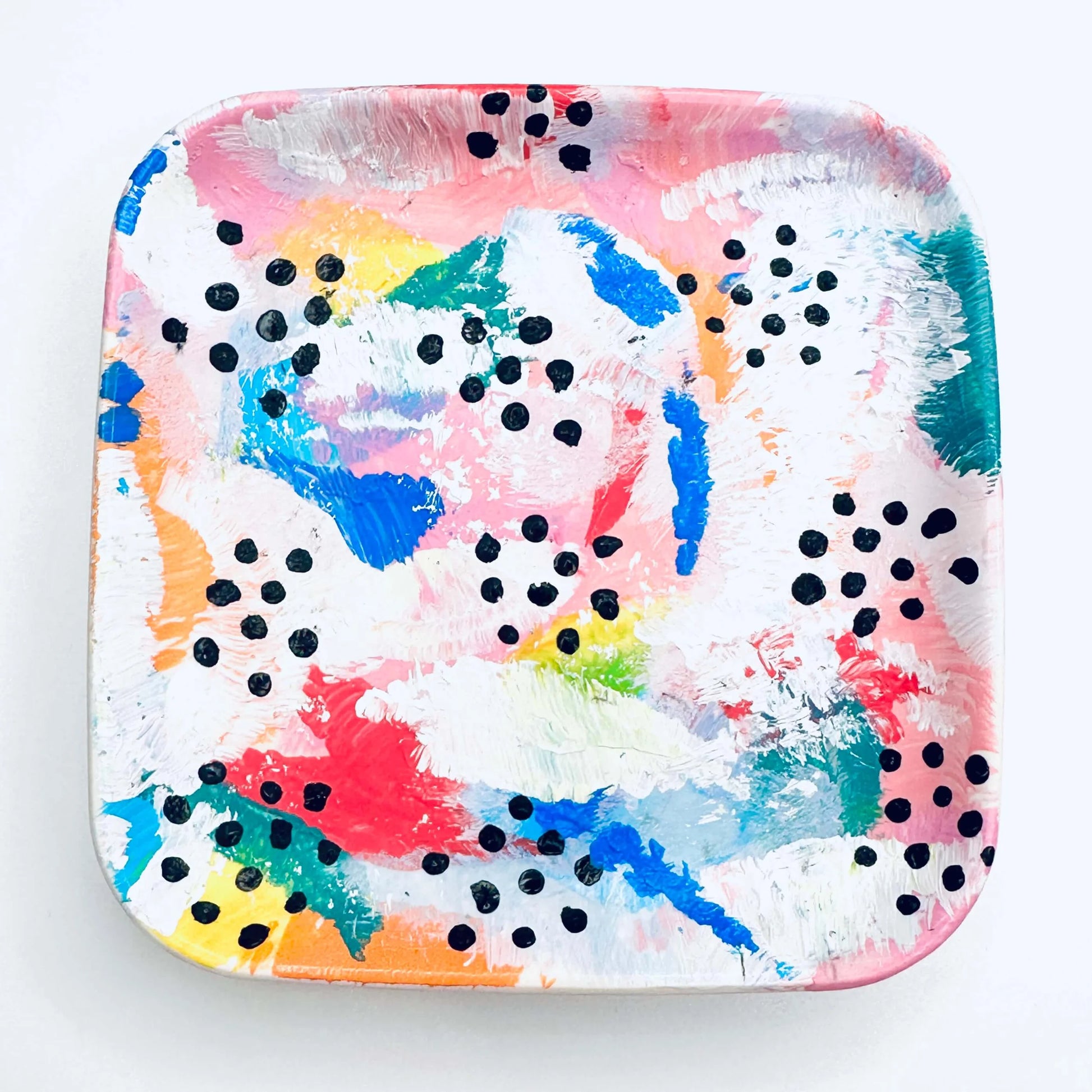 A hand-painted jewellery dish featuring vibrant splashes of blue, green, red, pink, orange, and white, with black dots.