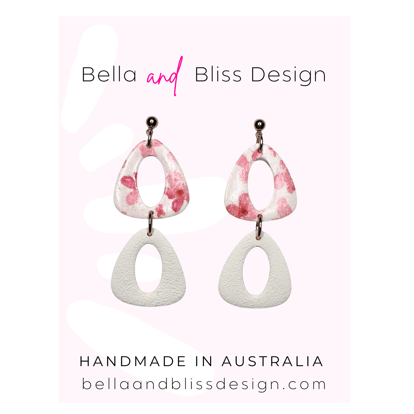 Pair of earrings with pink and white design on a light pink background, featuring 'Bella and Bliss Design'.