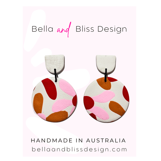 Pair of colorful earrings with 'Bella and Bliss Design' branding on a pink background.