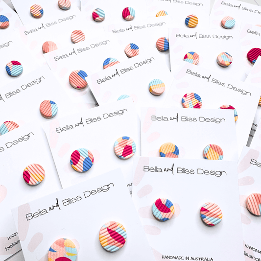 Colorful striped earrings on display with 'Bella and Bliss Design' branding.
