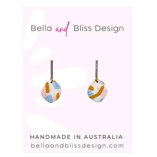 Colorful earrings with 'Bella and Bliss Design' branding on a pink gradient background.