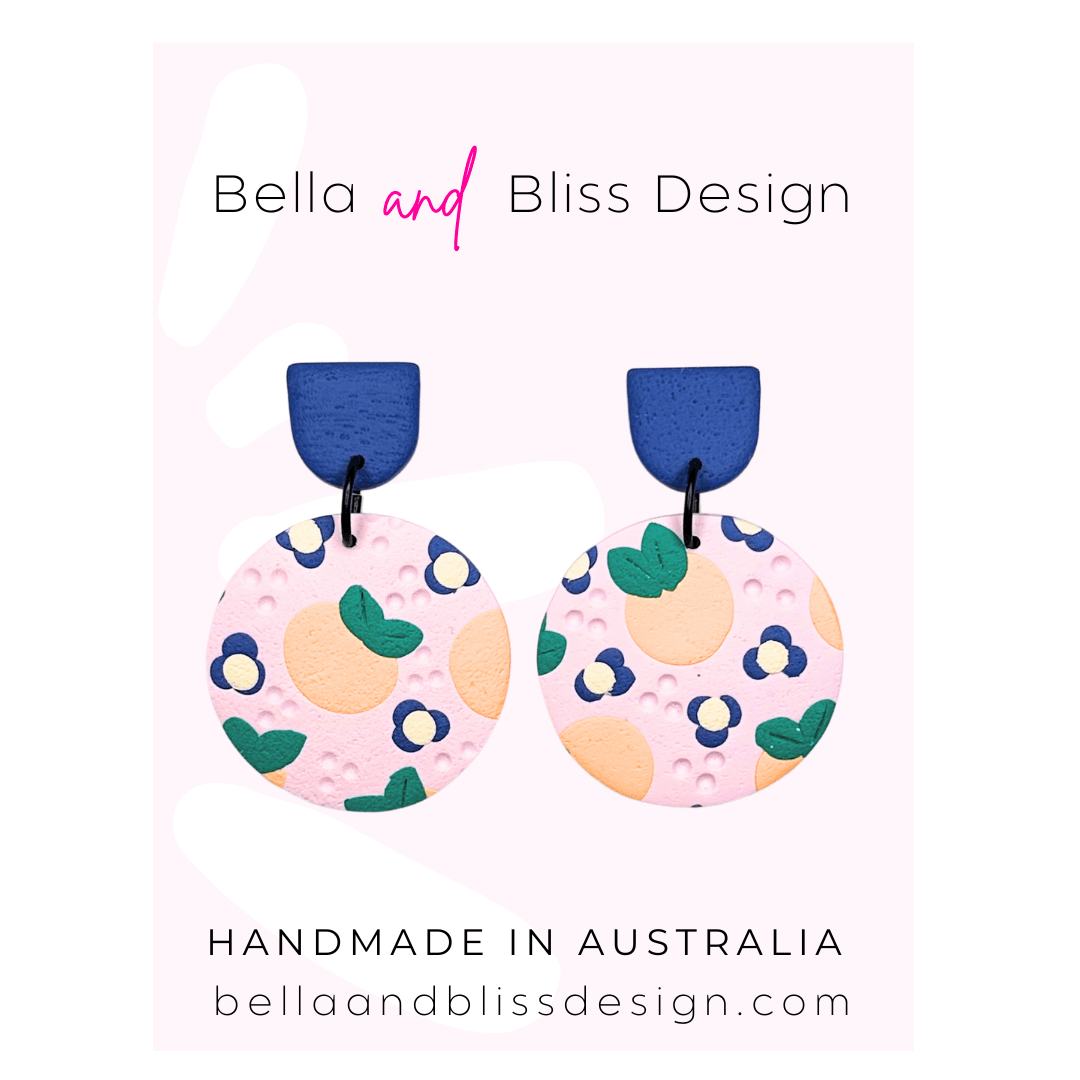 Peach Blossom Dangle Earrings with 'Bella and Bliss Design' branding on a pink background