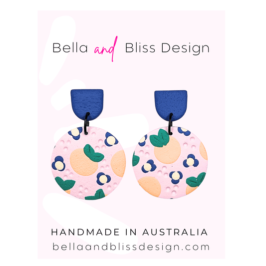 Peach Blossom Dangle Earrings with 'Bella and Bliss Design' branding on a pink background