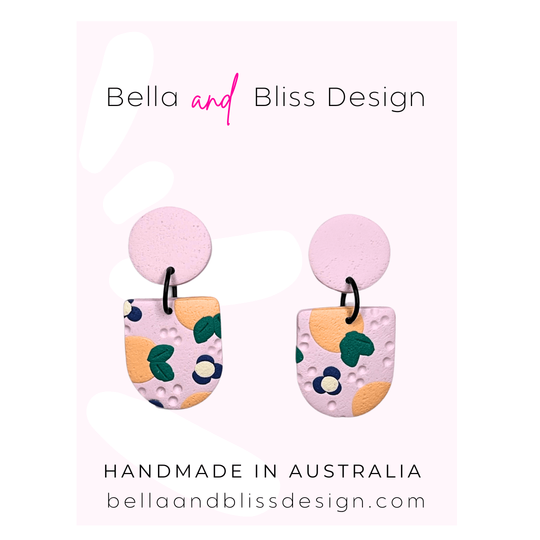 Peach Blossom Dangle Earrings with 'Bella and Bliss Design' branding on a pink background