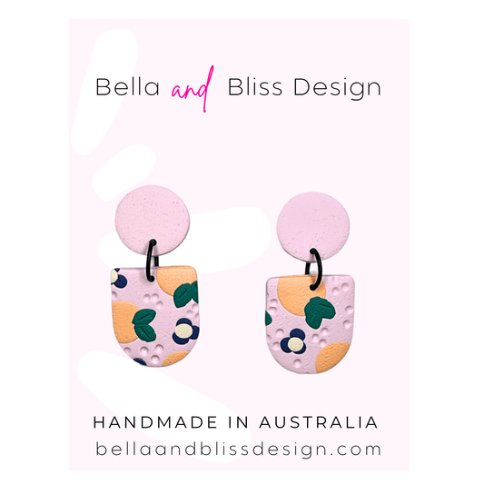 Peach Blossom Dangle Earrings with 'Bella and Bliss Design' branding on a pink background