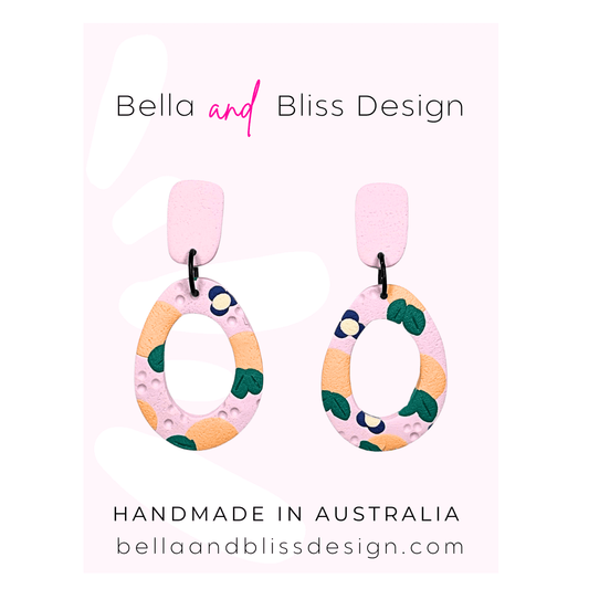 Peach Blossom Dangle Earrings with 'Bella and Bliss Design' branding on a pink background