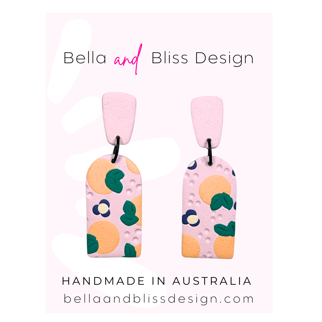 Peach Blossom Dangle Earrings with 'Bella and Bliss Design' branding on a pink background