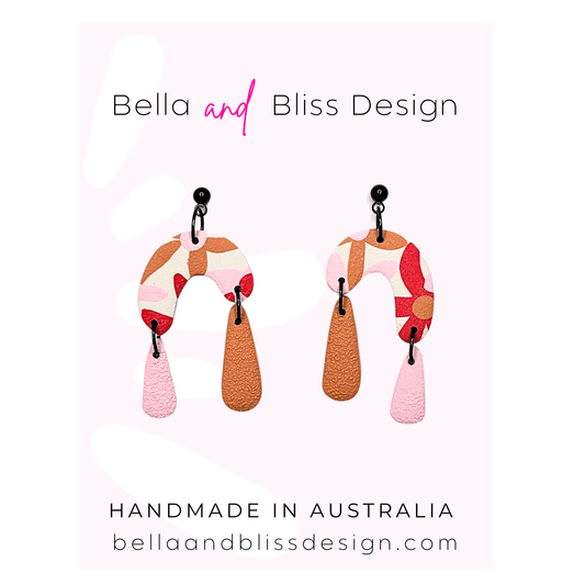 Colorful earrings with 'Bella and Bliss Design' branding on a light pink background.