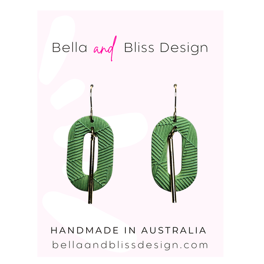 Green earrings with embossed design on a light pink background, featuring Bella and Bliss Design branding.
