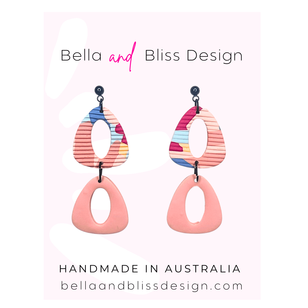 Colorful earrings with 'Bella and Bliss Design' branding on a pink background